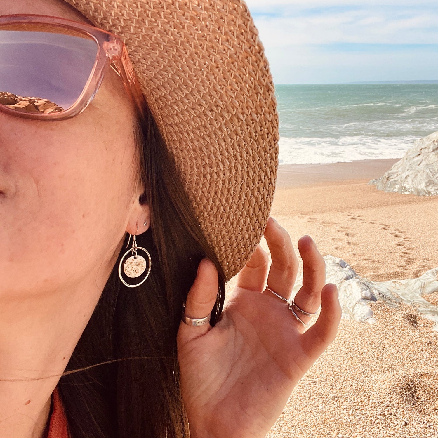 Person wearing a straw hat and sunglasses on a beach