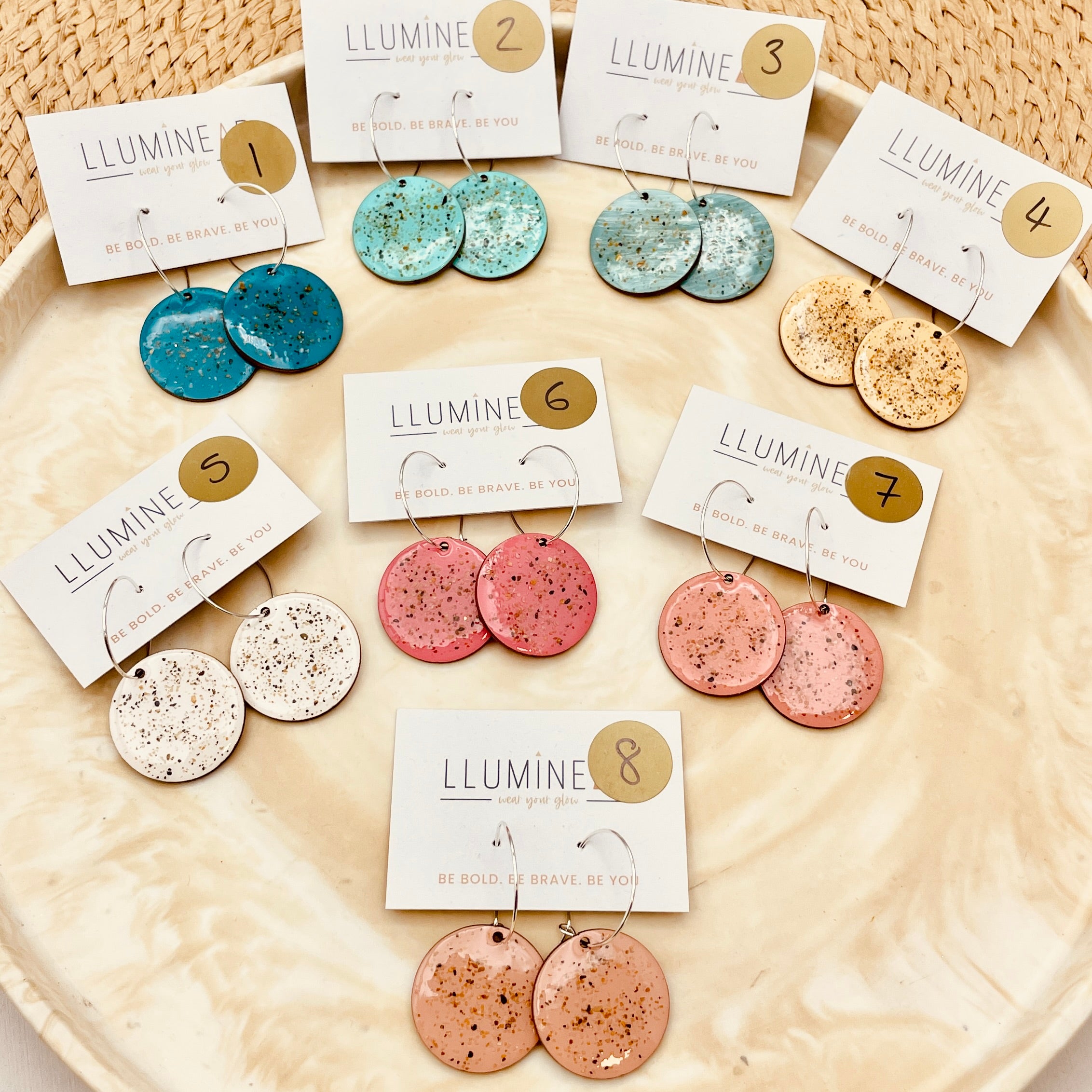 Collection of colorful earrings with tags on a textured surface