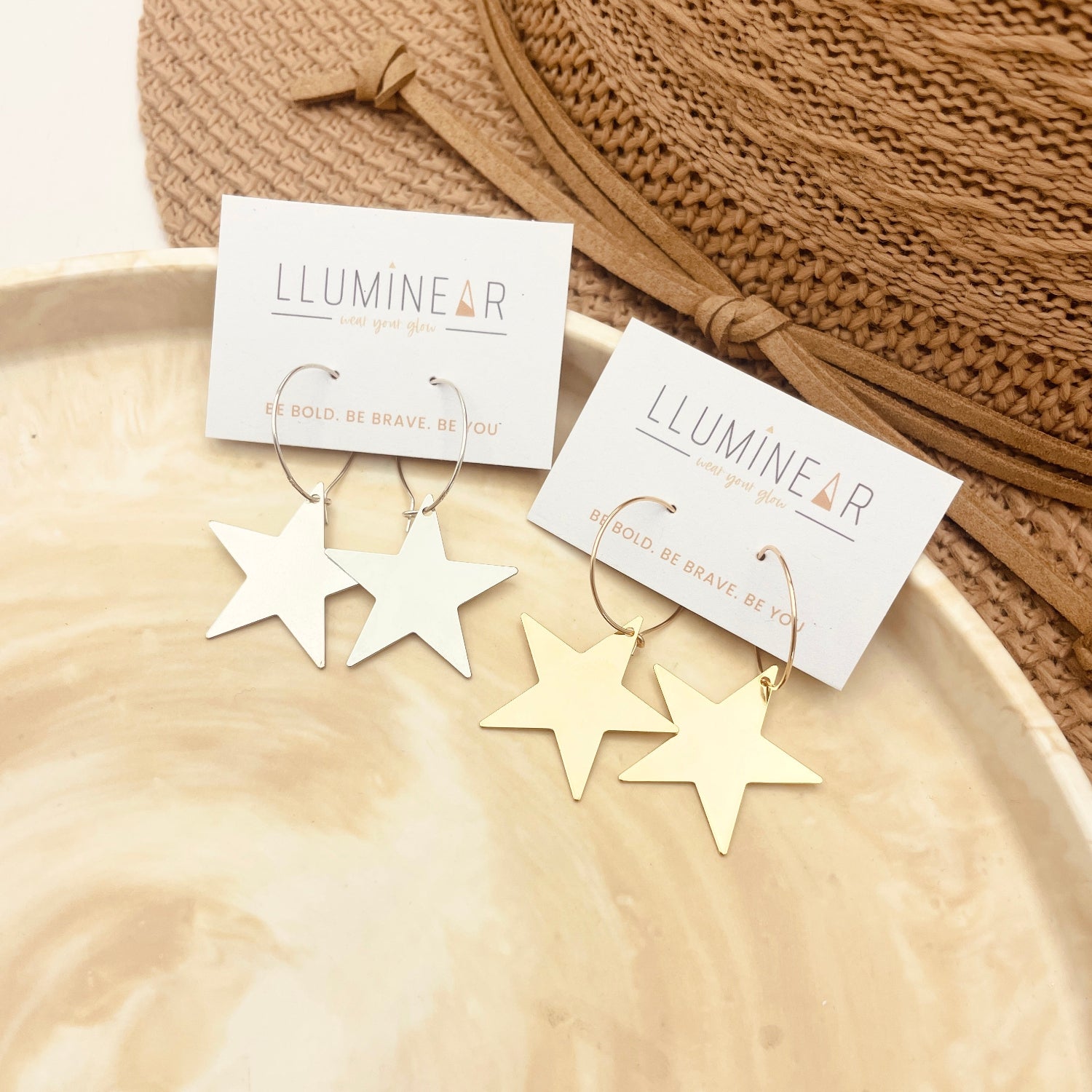 Gold star earrings on a beige surface with 'Lumineer' cards.