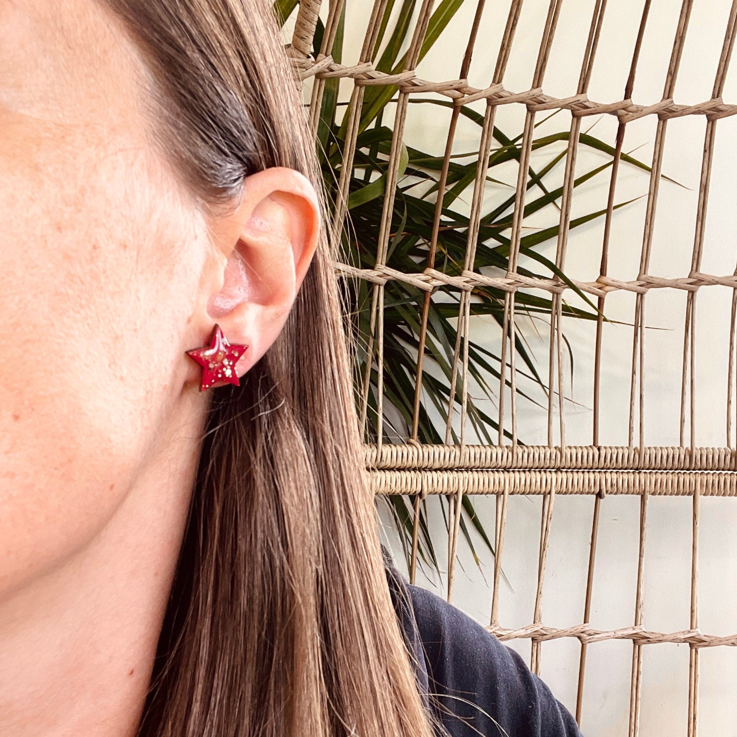 Close-up of a person wearing red earrings with a neutral background