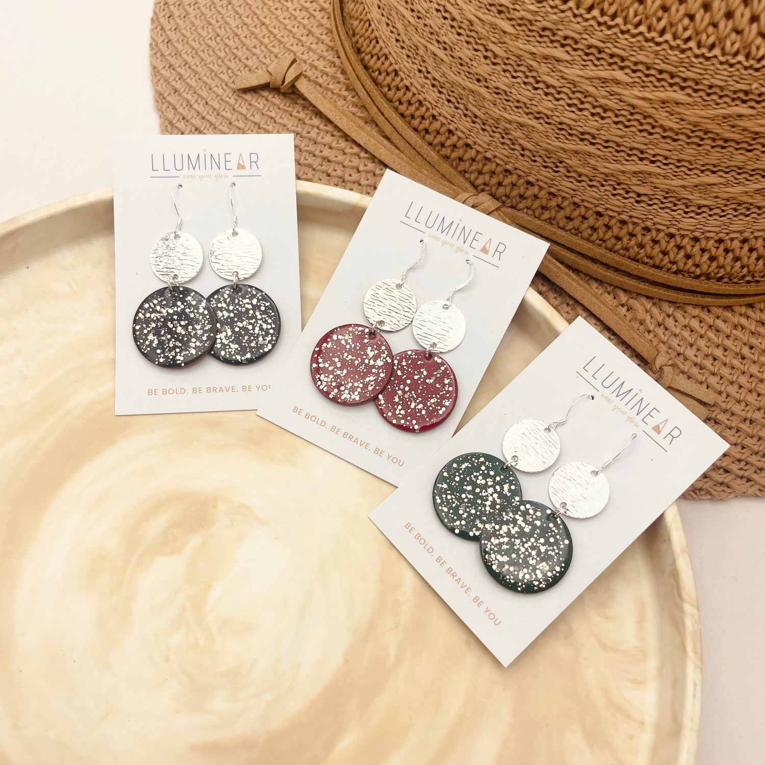 Earring packaging with glittery disc earrings on a wooden tray and knitted fabric background