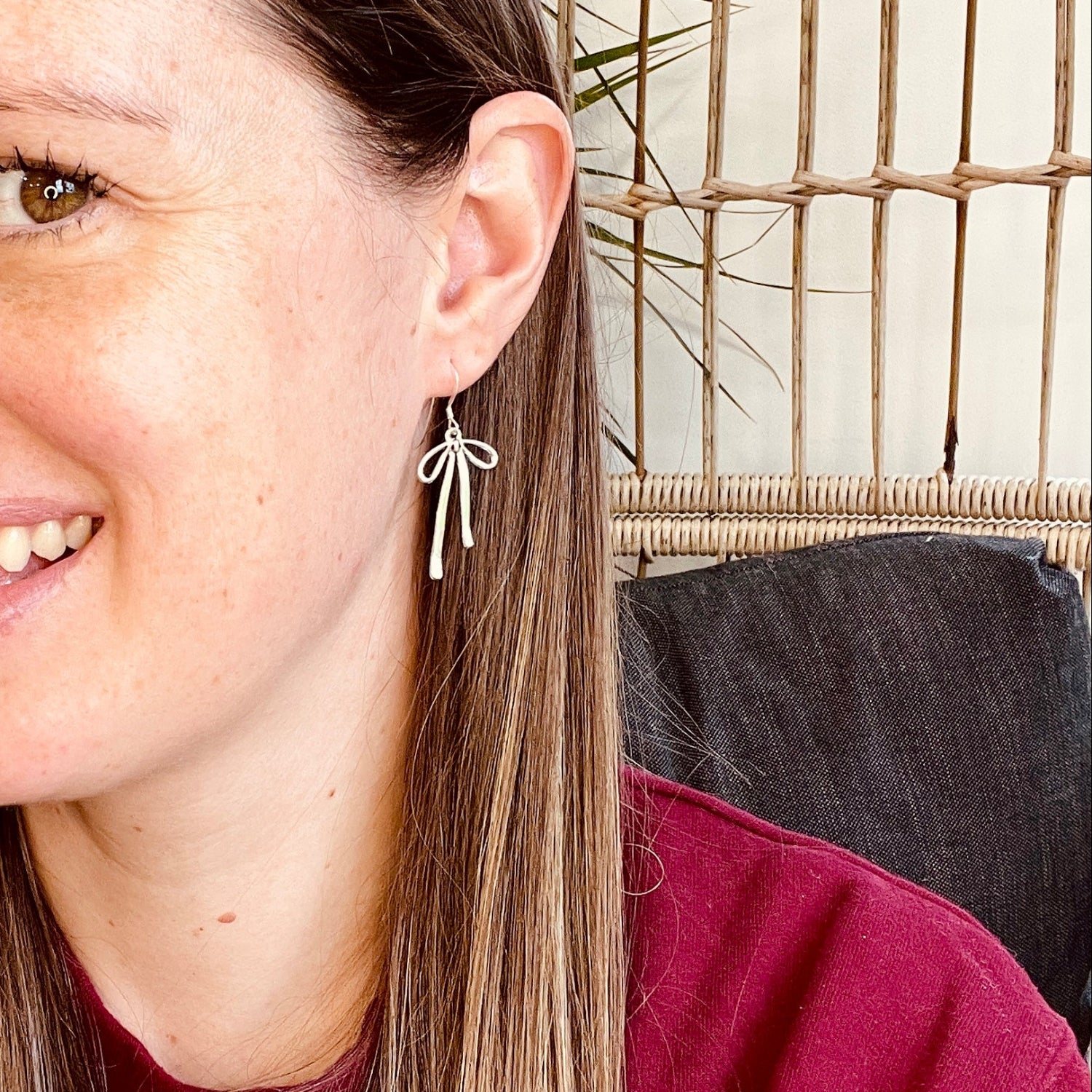 Woman with long brown hair wearing a red top in front of a woven wall.