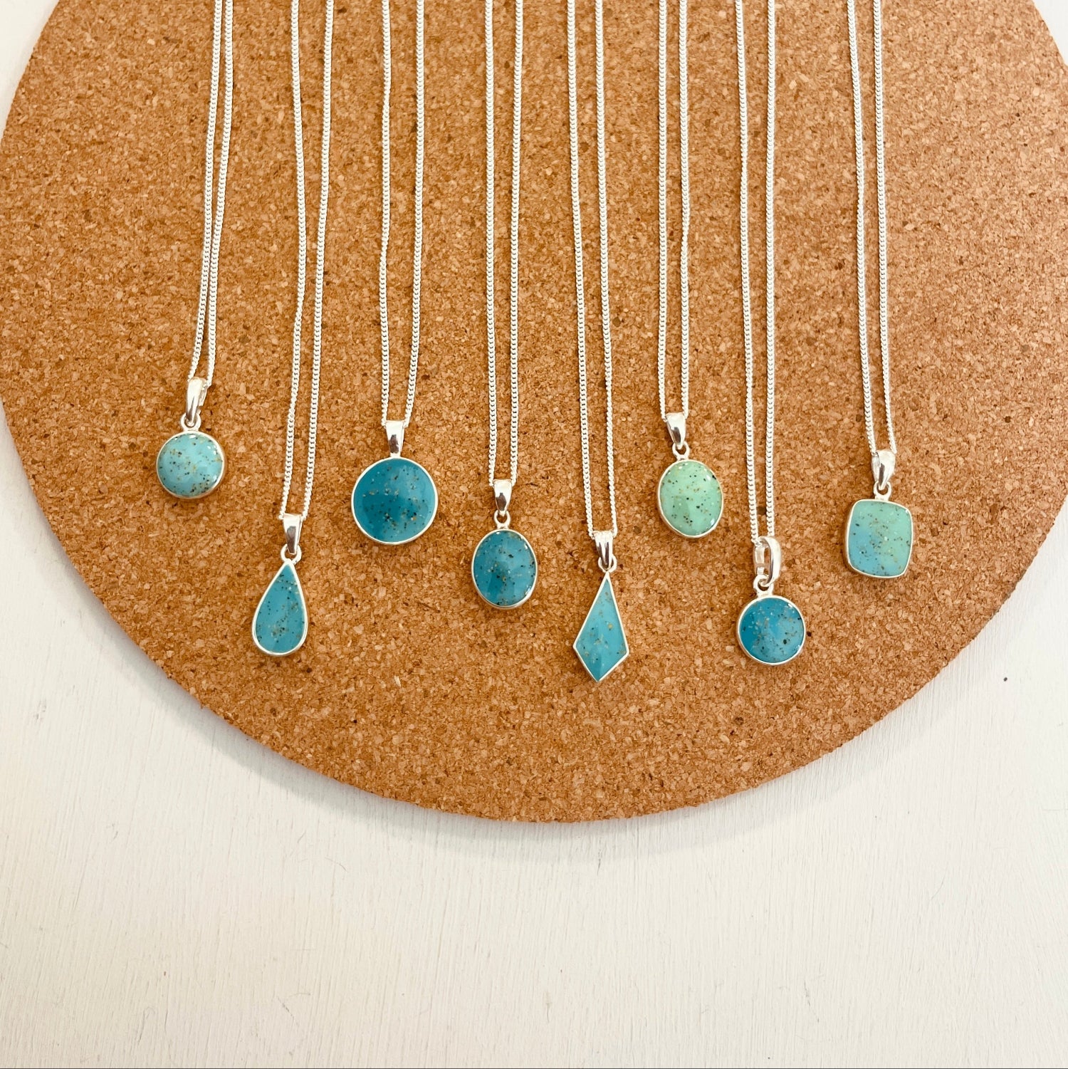 Necklaces with turquoise pendant stones on a cork board