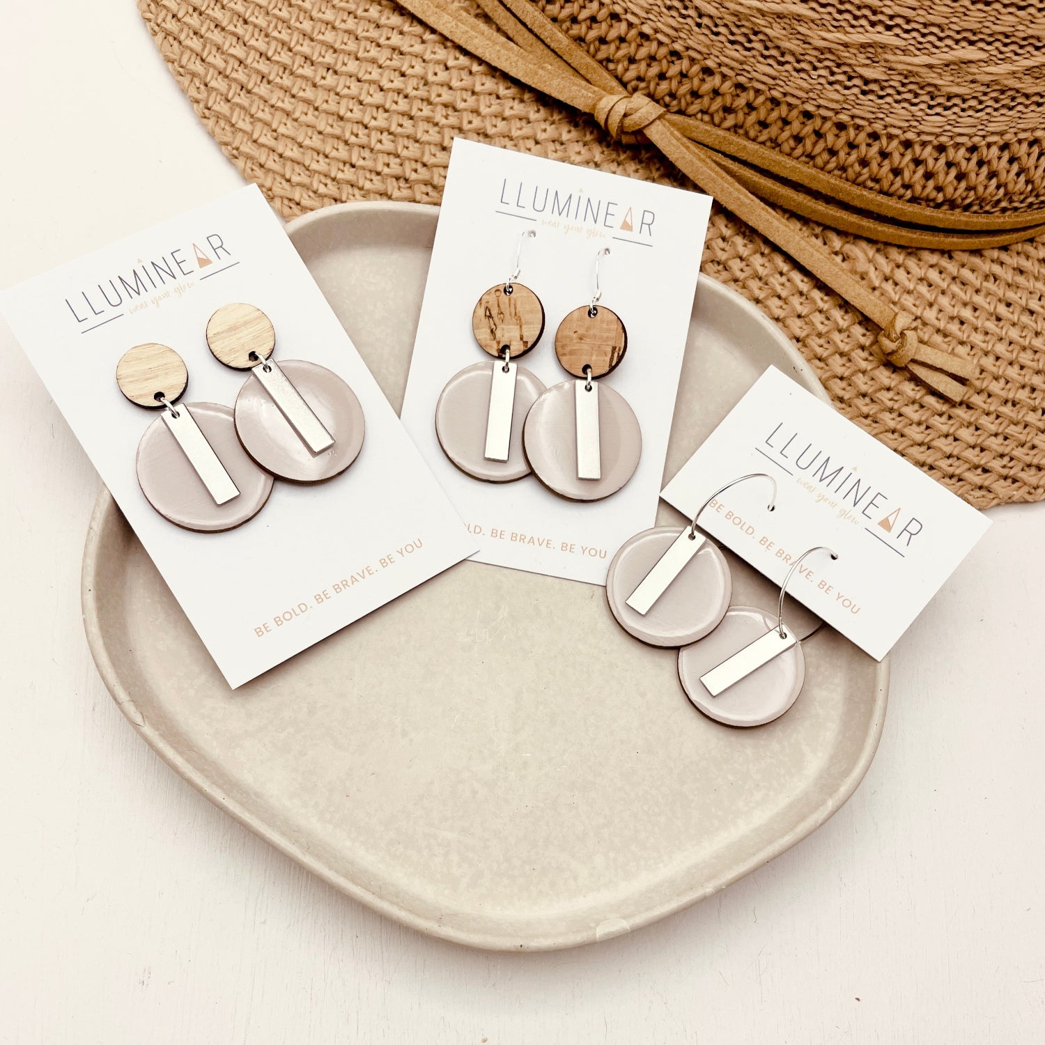 Earrings on display with packaging on a beige plate and white background